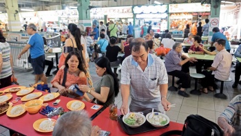 一位大叔在牛車(chē)水大廈熟食中(zhōng)心内，手托一個食物(wù)餐盤